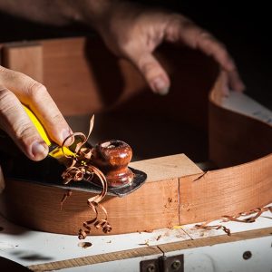 Primo piano di un liutaio che lavora al telaio di una chitarra in legno di palissandro