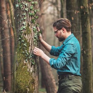 Un ricercatore accanto a un tronco d'albero in un fitto bosco