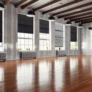 Un ampio spazio industriale ristrutturato con molti grandi finestroni e parquet scuro e molto lucido