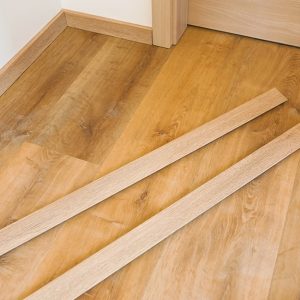 Due singole assi di battiscopa poggiate su un parquet