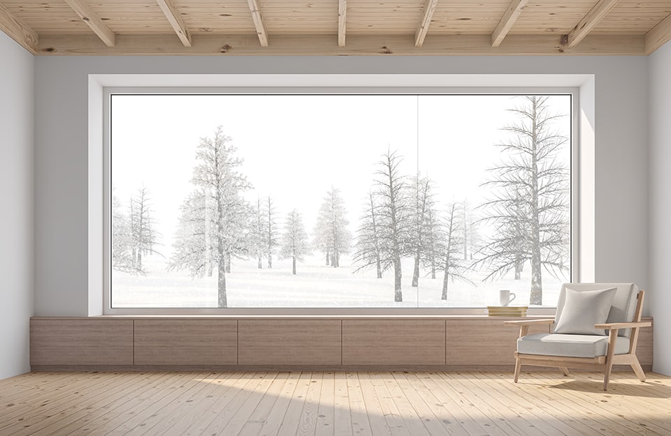 Stanza essenziale in legno di pino con enorme finestra affacciata su un panorama montano innevato