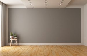 Stanza vuota con parquet in legno di pino, una sedia, parete color tortora e soffitto con faretti