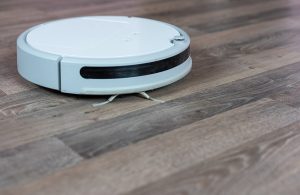 Un robot aspirapolvere bianco in azione su un parquet