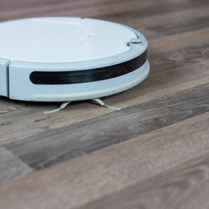 Un robot aspirapolvere bianco in azione su un parquet