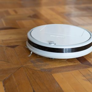 Aspirapolvere robot bianco su un parquet antico