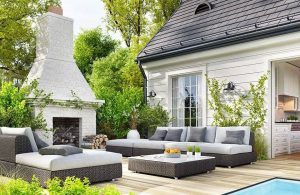 Il giardino di una villetta con un salotto esterno su decking con tanto di grande camino