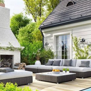 Il giardino di una villetta con un salotto esterno su decking con tanto di grande camino