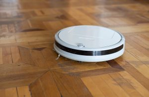 Aspirapolvere robot bianco su un parquet antico