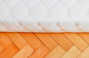 Dettaglio di un materasso poggiato su un parquet a spina di pesce