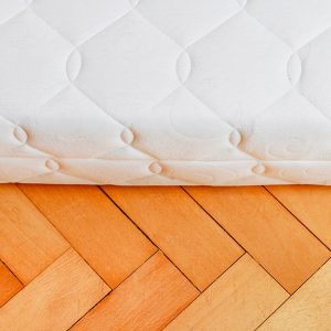 Dettaglio di un materasso poggiato su un parquet a spina di pesce