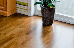 Dettaglio del parquet interno di un'abitazione, in legno di ovangkol, con un vaso in vimini davanti a una luminosa finestra