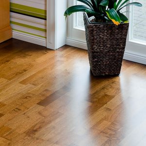 Dettaglio del parquet interno di un'abitazione, in legno di ovangkol, con un vaso in vimini davanti a una luminosa finestra