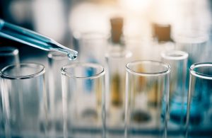 Delle provette in laboratorio con un contagocce che versa un liquido azzurro in una di esse