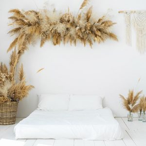 Una stanza da letto tutta sui toni del bianco e in stile Boho Chic, con materasso sul parquet e decorazioni