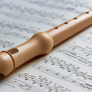 Un flauto in legno di pero poggiato sopra a uno spartito musicale