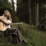 La cantautrice Erica Boschiero suona la chitarra tra gli alberi di una foresta