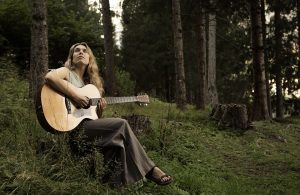 La cantautrice Erica Boschiero suona la chitarra tra gli alberi di una foresta