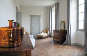 Il corridoio di un'antica casa francese con un vecchio parquet da restaurare e qualche mobile