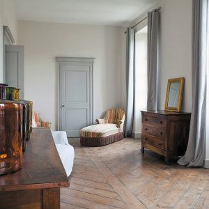 Il corridoio di un'antica casa francese con un vecchio parquet da restaurare e qualche mobile