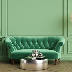 Angolo di un salotto in stile vintage con boiserie a cornici verde pastello, sofà trapuntato verde