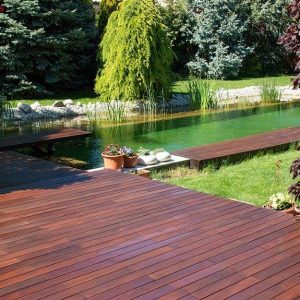 Decking in legno di cumari su lago artificiale in un grande giardino