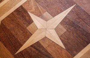 Dettaglio di un parquet intarsiato, con rosone a stella e diverse essenze legnose utilizzate