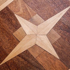 Dettaglio di un parquet intarsiato, con rosone a stella e diverse essenze legnose utilizzate