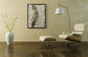 Un salotto stile modernista essenziale con poltrona Eames Lounge Chair, grande vaso bianco, quadro di arte astratta, lampada da terra e parquet in ebano