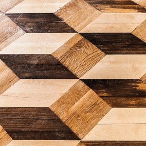 Dettaglio di un pavimento a parquet intarsiato con motivi a rombi in tre diverse essenze, che danno l'idea di cubi