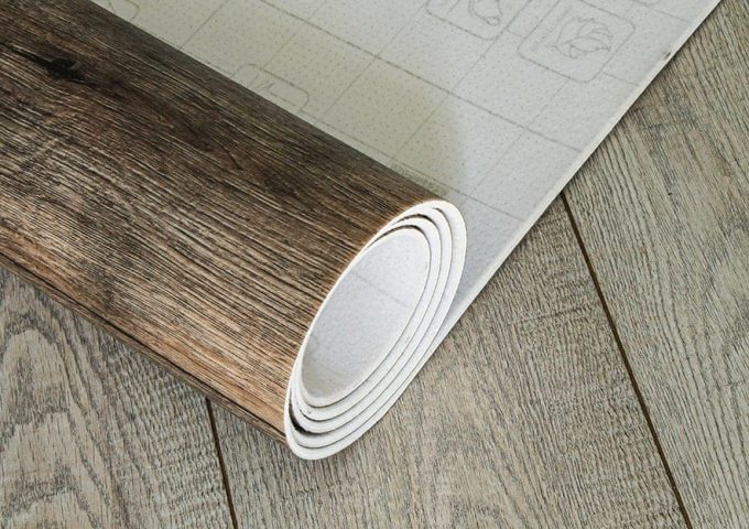 Un rotolo di linoleum effetto-parquet steso su un pavimento in lineolum dello stesso tipo