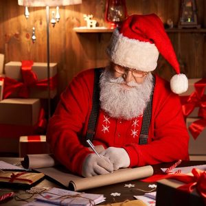 Babbo Natale compila una lista nella sua casa di legno, circondato da regali