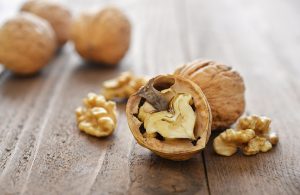 Delle noci su un parquet. Sono tutte chiuse tranne una, con il guscio a metà e parte del gheriglio dentro, mentre le parti rimanenti sono sparse per il pavimento
