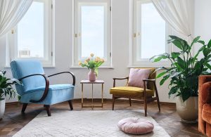 Un luminoso salotto con mobili vintage di diversi colori, parquet e grande tappeto chiaro