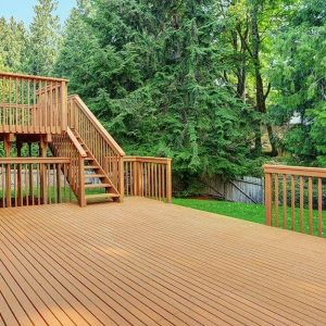 Grande decking esterno di una casa immersa nel verde, con scale che conducono al piano superiore
