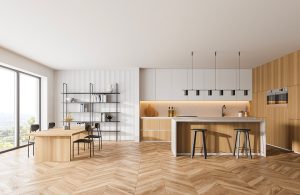 Un luminoso open space con cucina e sala da pranzo in legno, parquet e grande finestra affacciata sul verde