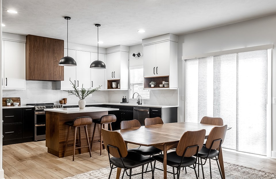 Luminoso open space con cucina e sala da pranzo sui toni del bianco, del nero e del legno scuro. Il pavimento a parquet è a listoni di colore naturale e con finitura opaca