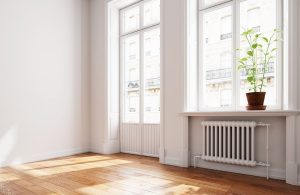 Luminosa stanza vuota con finestra e portafinestra, pareti bianche e parquet color miele