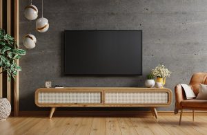 Tv a muro e mobiletto orizzontale in legno in una salotto con parquet e parete in cemento