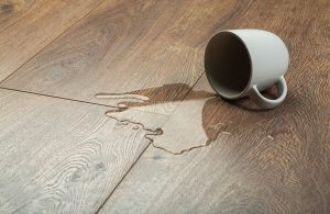 Una tazza rovesciata su un parquet, con dell'acqua fuoriuscita