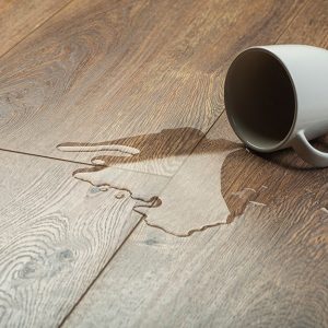 Una tazza rovesciata su un parquet, con dell'acqua fuoriuscita