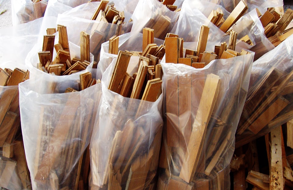 Dei sacchi bianchi semitrasparenti con dentro, in verticale, delle assi di legno scartate