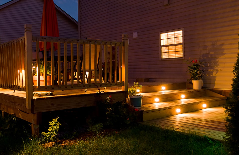 Decking esterno di una casa di notte, con luci a LED accese incassate nei gradini di una piccola scala in legno