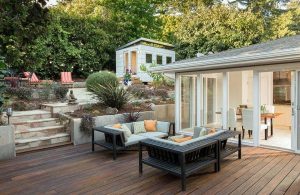 Giardino su diversi livelli, con elementi in pietra, cespugli, statuette giapponesi, sdraio e decking in legno
