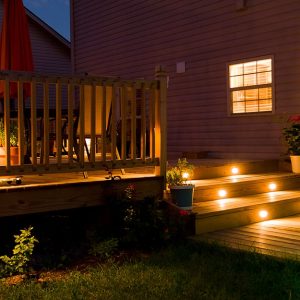 Decking esterno di una casa di notte, con luci a LED accese incassate nei gradini di una piccola scala in legno