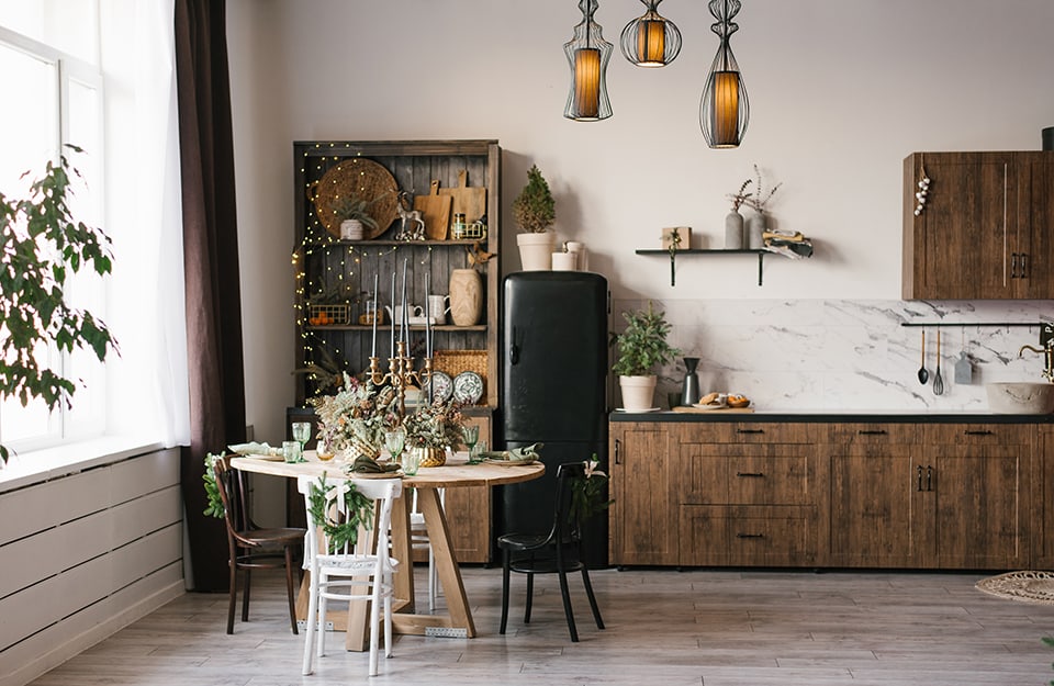 Luminosa e ampia cucina in stile rustrial in una casa di campagna, con mobili in legno, frigorifero nero e parquet al pavimento