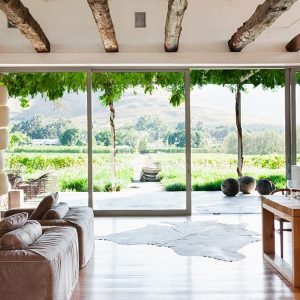 Luminoso salotto in casa di campagna con travi a vista, parete completamente finestrata,