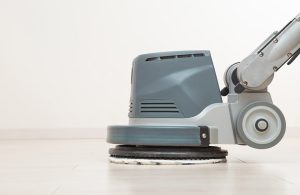 Primo piano su una lucidatrice professionale che sta passando la cera su un parquet bianco