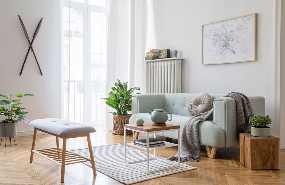 Elegante e luminoso soggiorno in stile scandinavo con sofà color menta, mobili, mappa poster, piante ed eleganti accessori