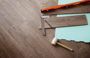 Un parquet in fase di posa con gli strumenti del mestiere, tra i quali mazza, squadra e livella
