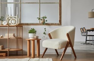 Angolo di un salotto in stile scandinavo con mobili in legno, poltrona, libreria, sgabello con sopra un vaso